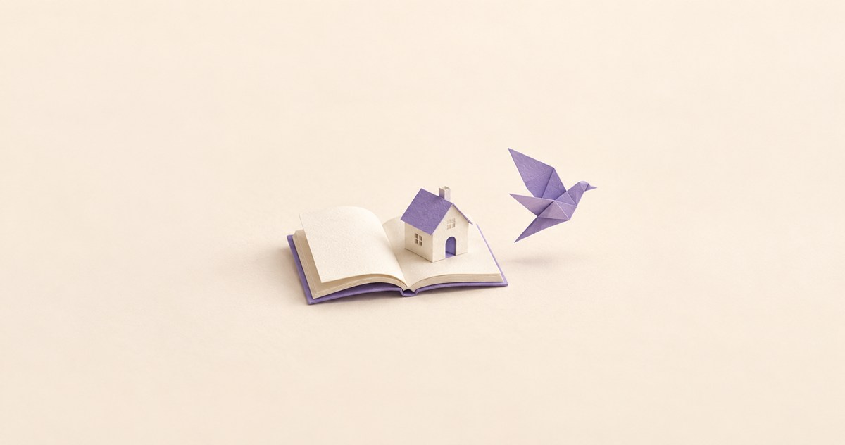 開いた紙の本と小さな家、その本の端から飛び立つように置かれた紫の紙の鳥