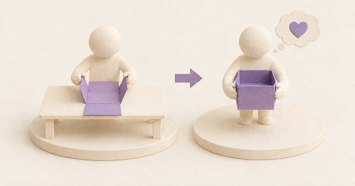 紙の収納箱を自分で組み立て、完成した箱を大切に持つ人の思いを小さなハートで示した紙模型